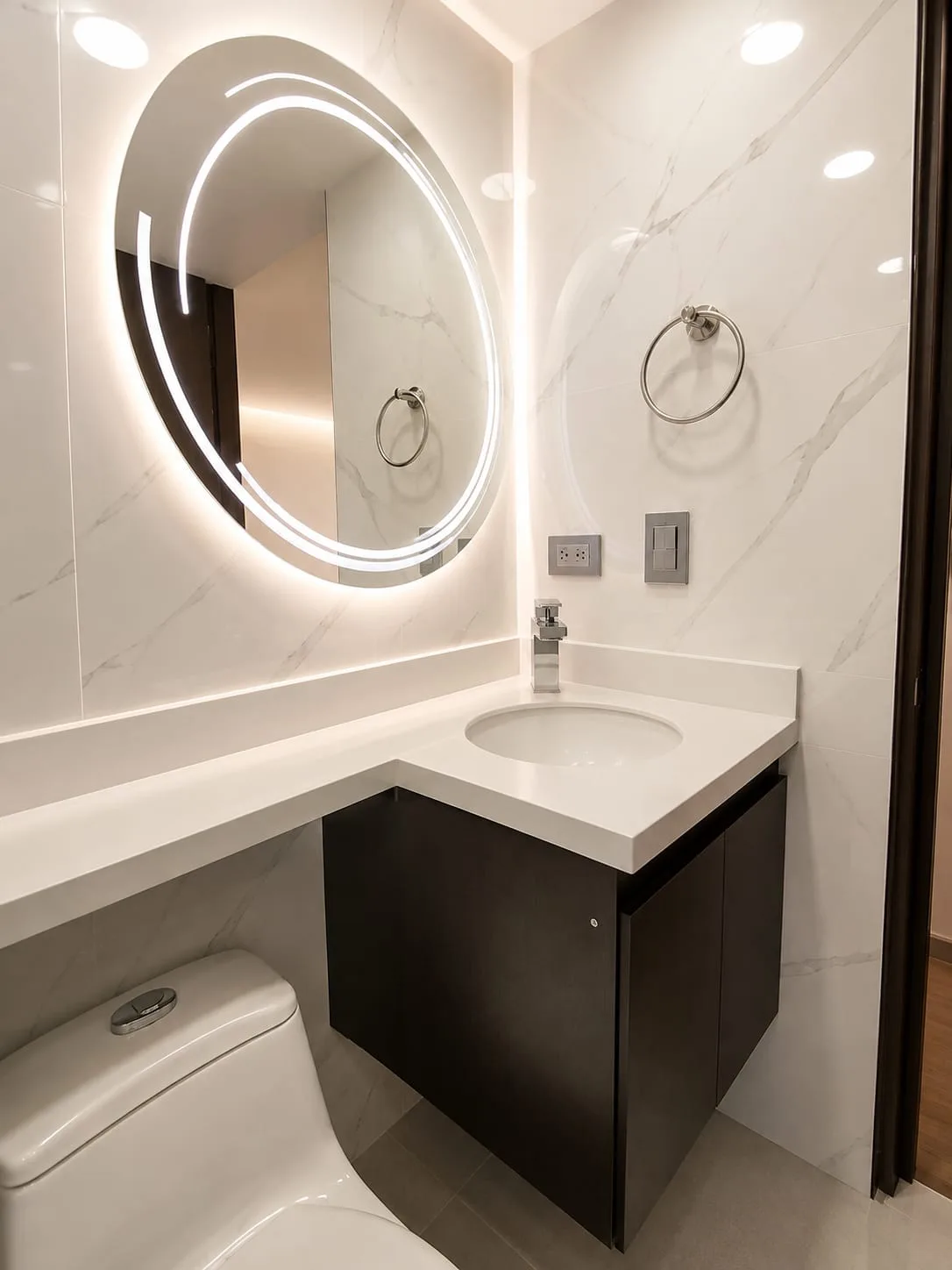 Baño en mármol con mueble oscuro y espejo LED circular