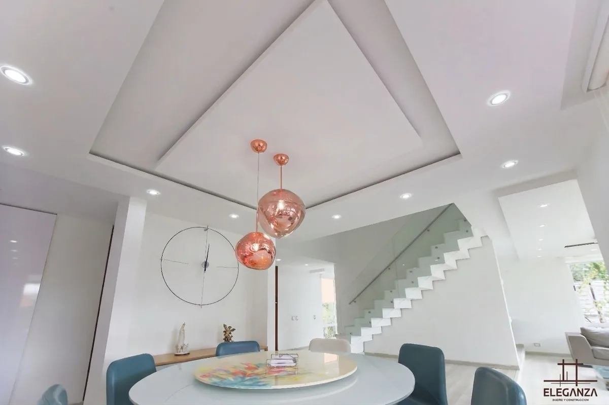 Comedor redondo con escaleras en vidrio y luces cobre