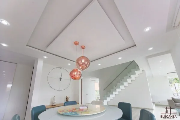Comedor redondo con escaleras en vidrio y luces cobre