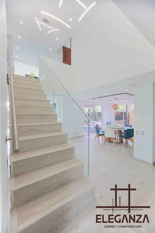Escalera en madera y vidrio con comedor de doble altura