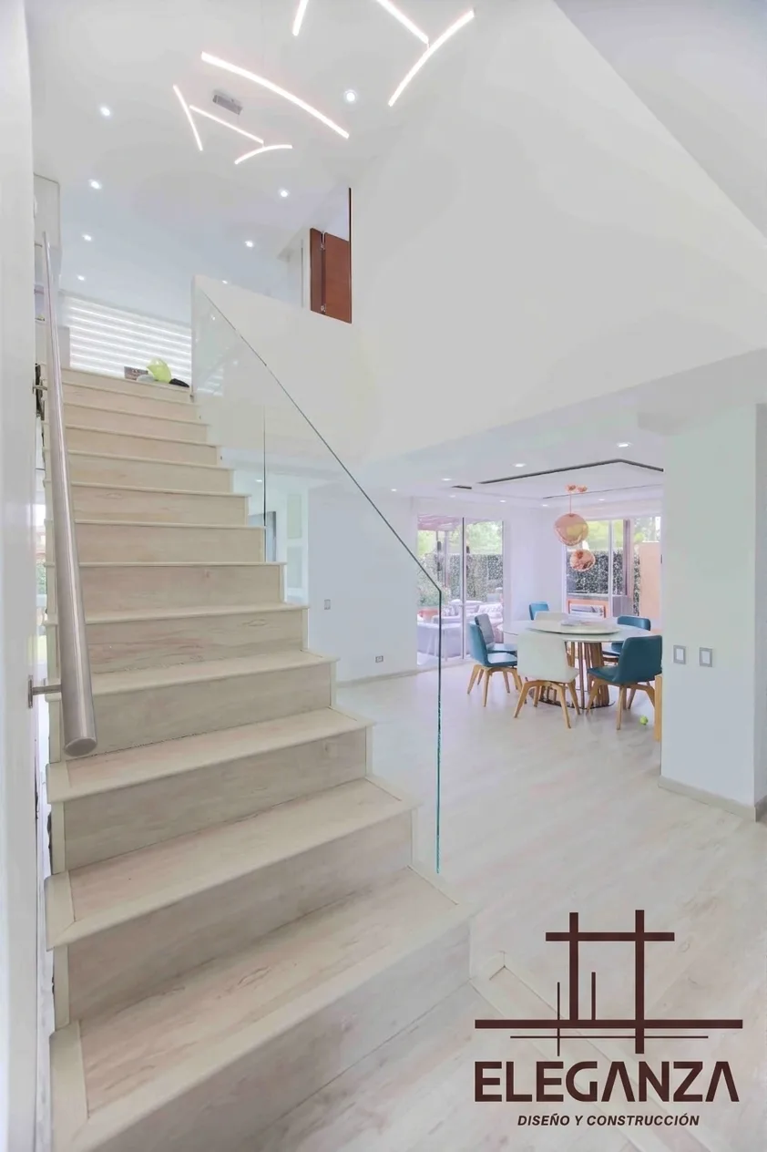 Escalera en madera y vidrio con comedor de doble altura